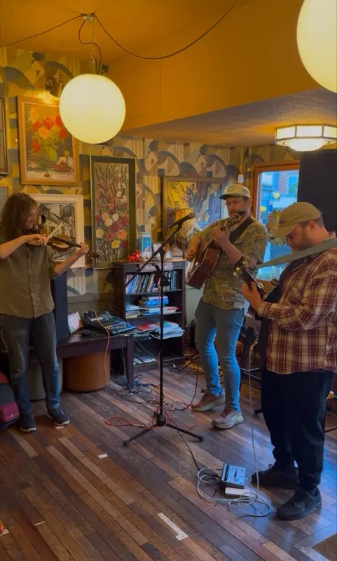 A trio playing fiddle, guitar and mandolin among the pictures at Pedro Lounge