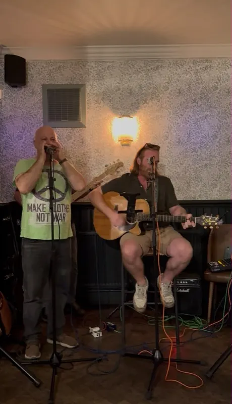A harmonica player and guitarist performing together at The Oak