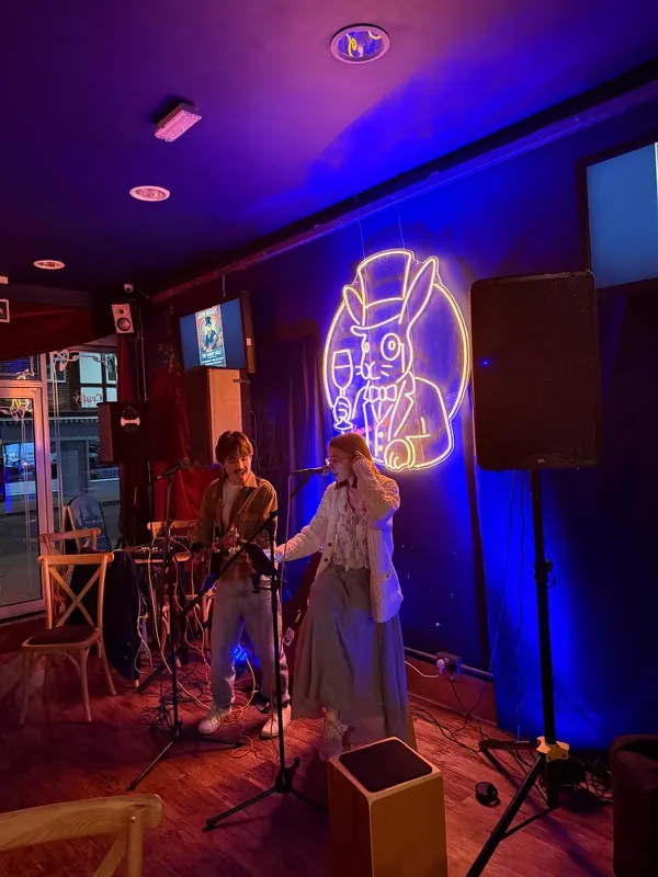 Two singers performing beneath the neon rabbit sign at The Rabbit Hole